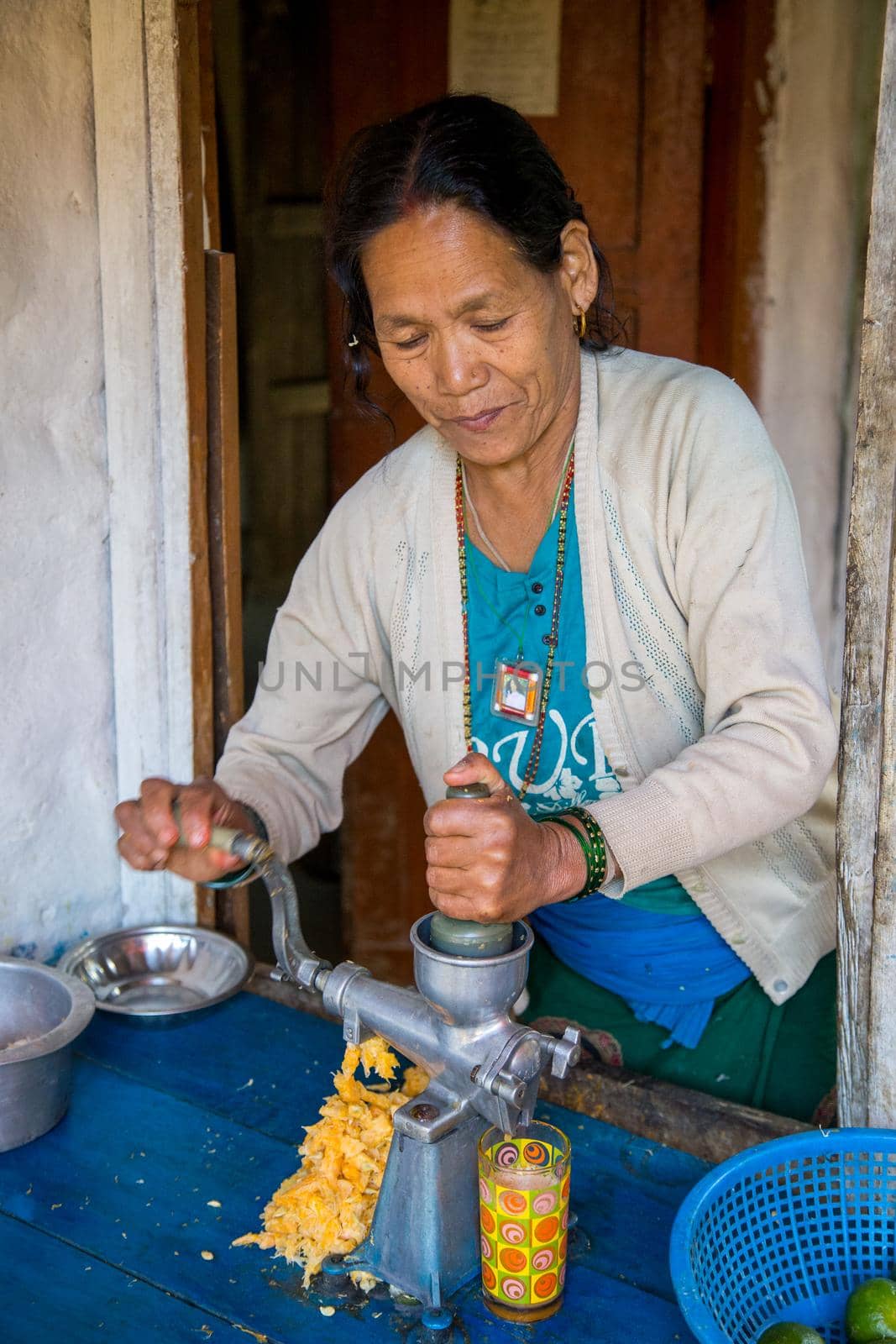 Annapurna Region, Nepal - October 24, 2014: An elderly lady hand pressing fresh orange juice.