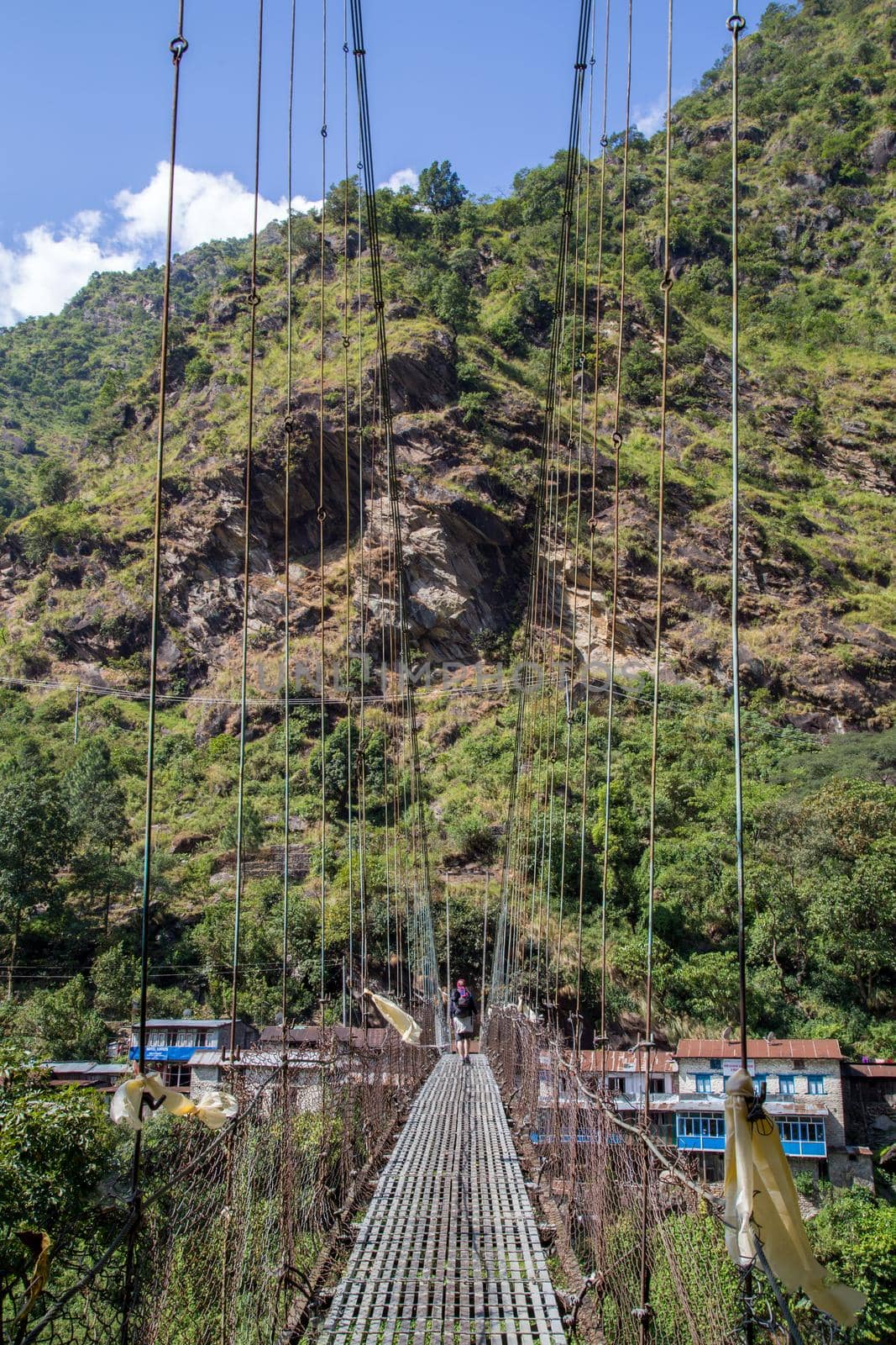 Annapurna Region - October 25, 2014: A hiker corssing a suspension bridge in the Annapurna region