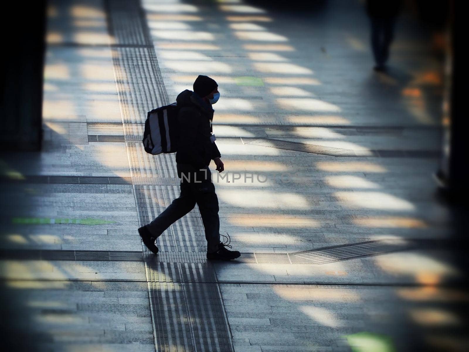 Unrecognizable lonely man silhouette walking wearing protective mask in train station Turin Italy January 13 2021 by lemar