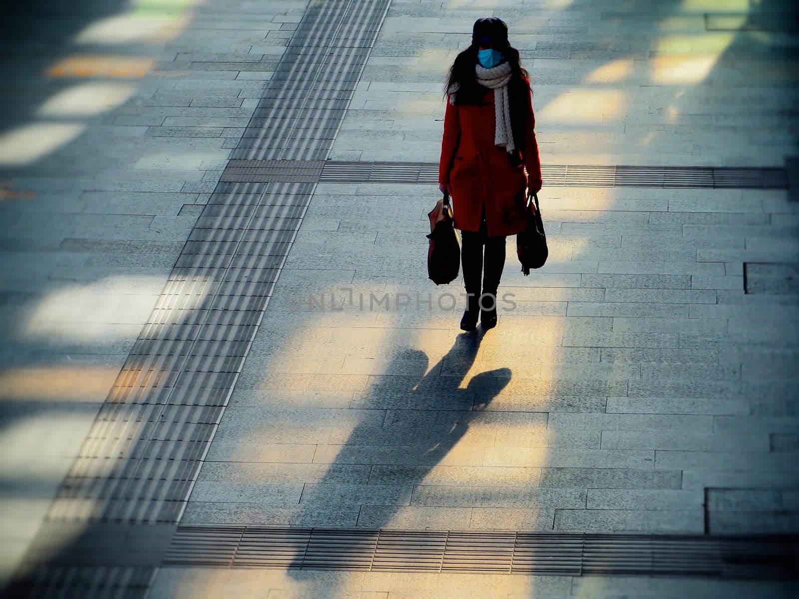 Unrecognizable lonely woman walking wearing protective mask on grainy stone sidewalk Turin Italy January 13 2021 by lemar