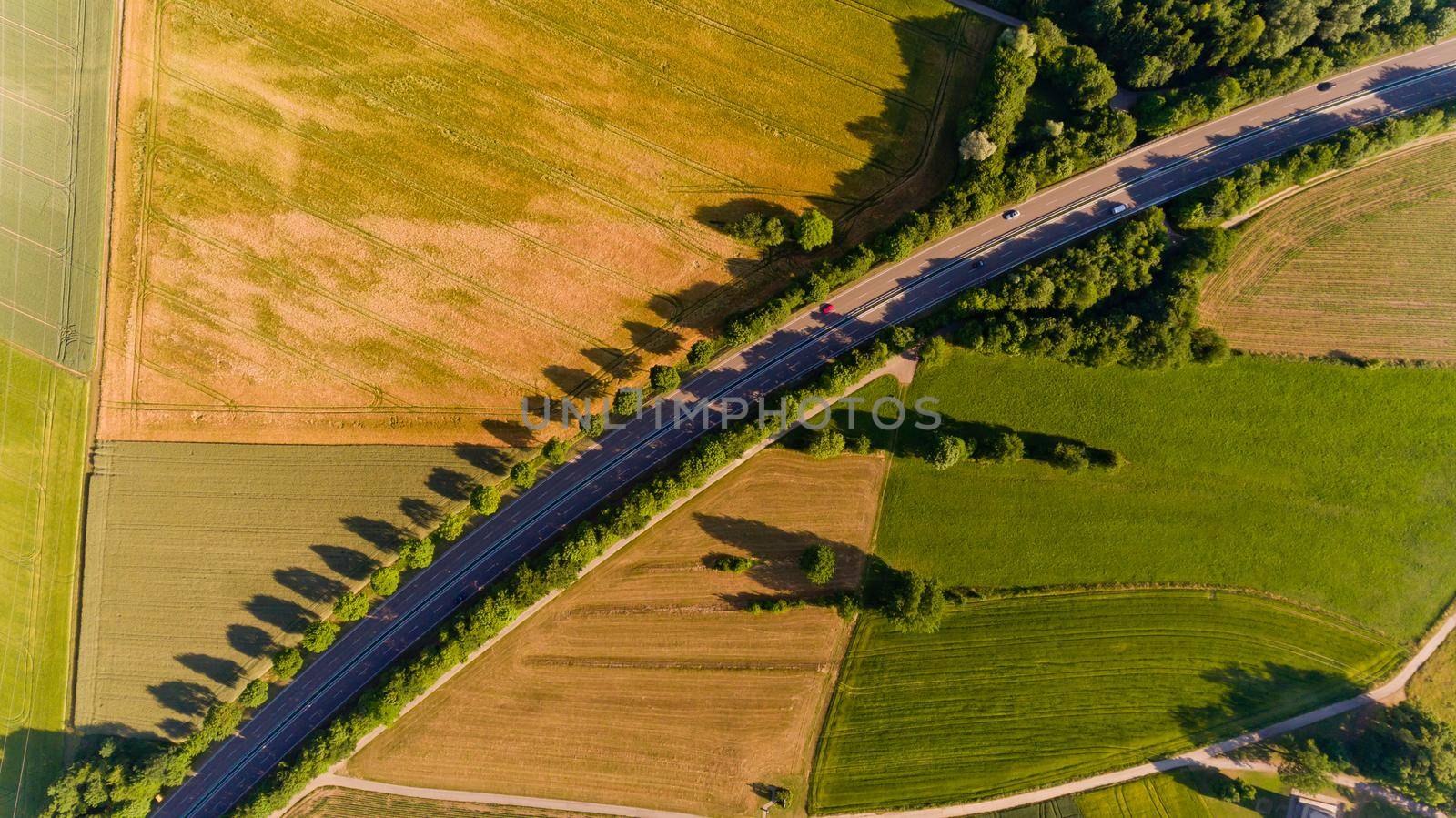 Top view of asphalt road passes through the field.