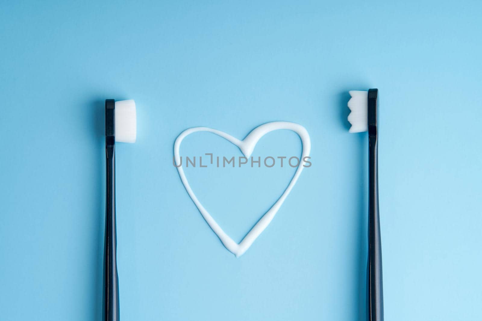 Heart shaped toothpaste between two toothbrushes close up by Try_my_best