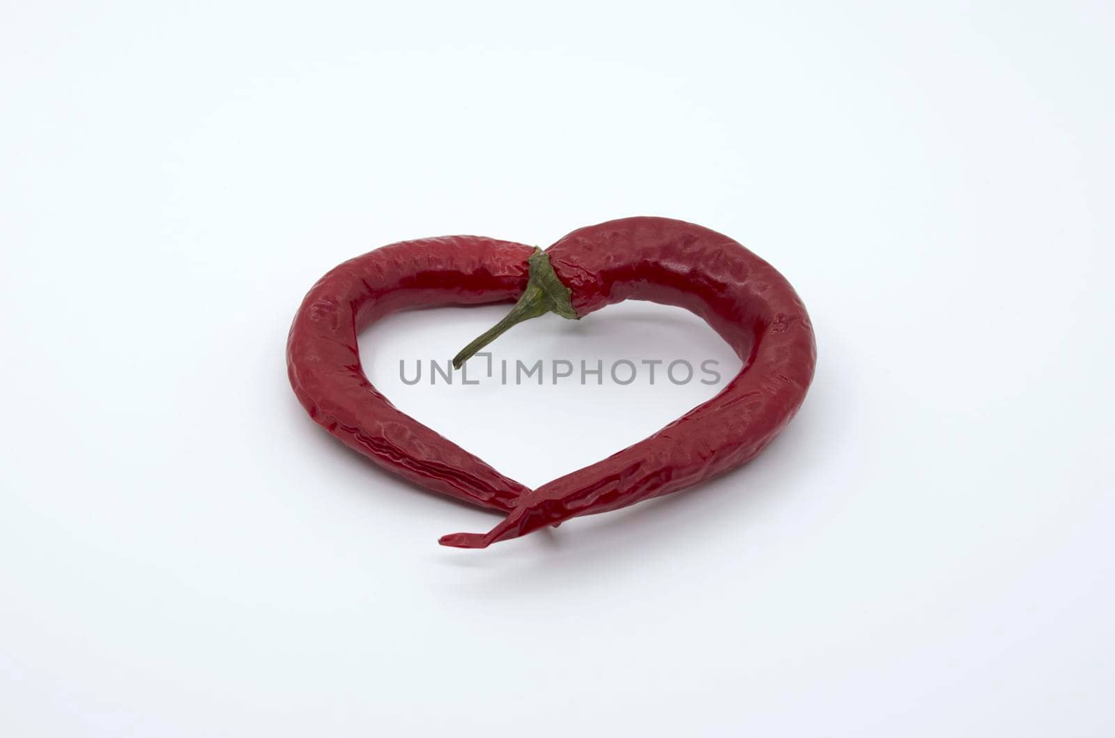 Heart of two red hot peppers on a white background.