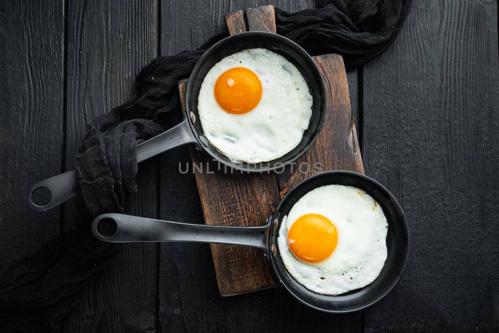 Fried Egg with ingredient in cast iron frying pan, on black wooden table background, top view flat lay