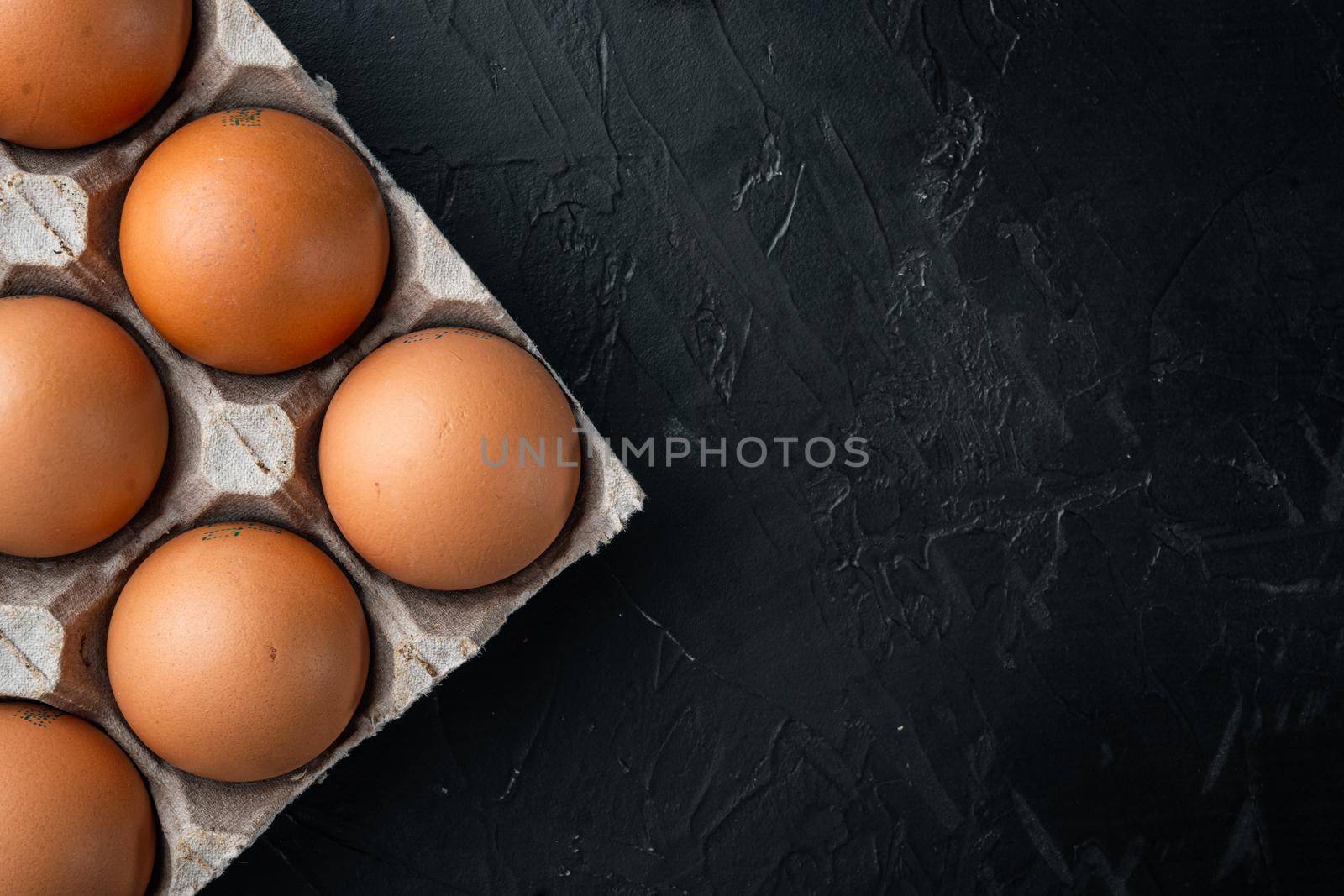 Brown eggs in carton box tray set, on black background, top view flat lay , with space for text copyspace