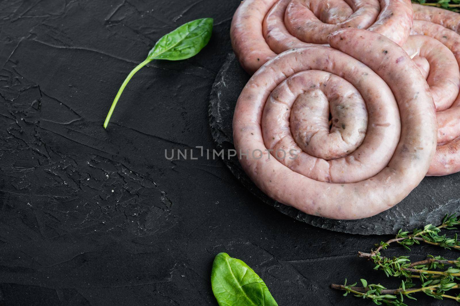 Raw snail sausage in traditional spiral set, on black background , with space for text copyspace