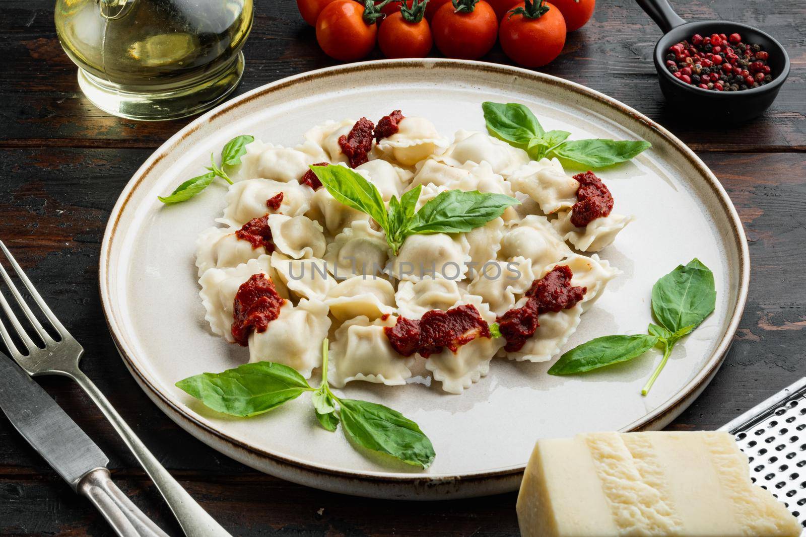 Ravioli pasta with mushroom cream sauce and cheese - Italian food style set with basil parmesan and tomatoe on white plate on old dark wooden table background