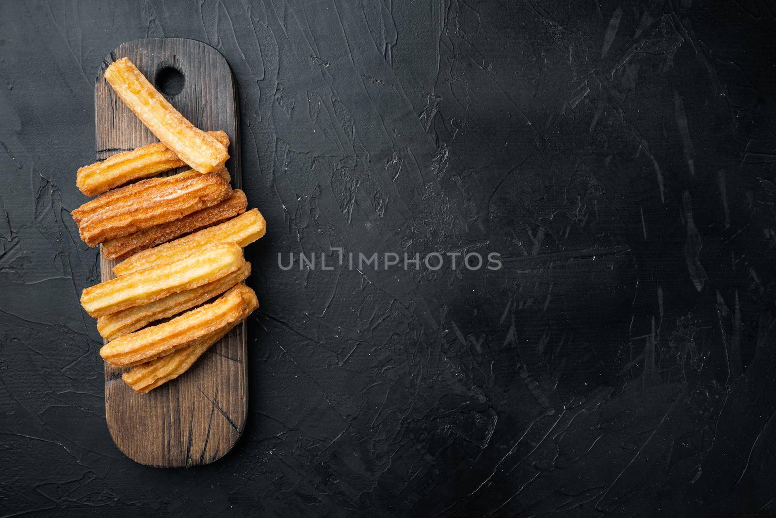 Churros sprinkled with powdered sugar set, on black background, top view flat lay with space for text, copyspace