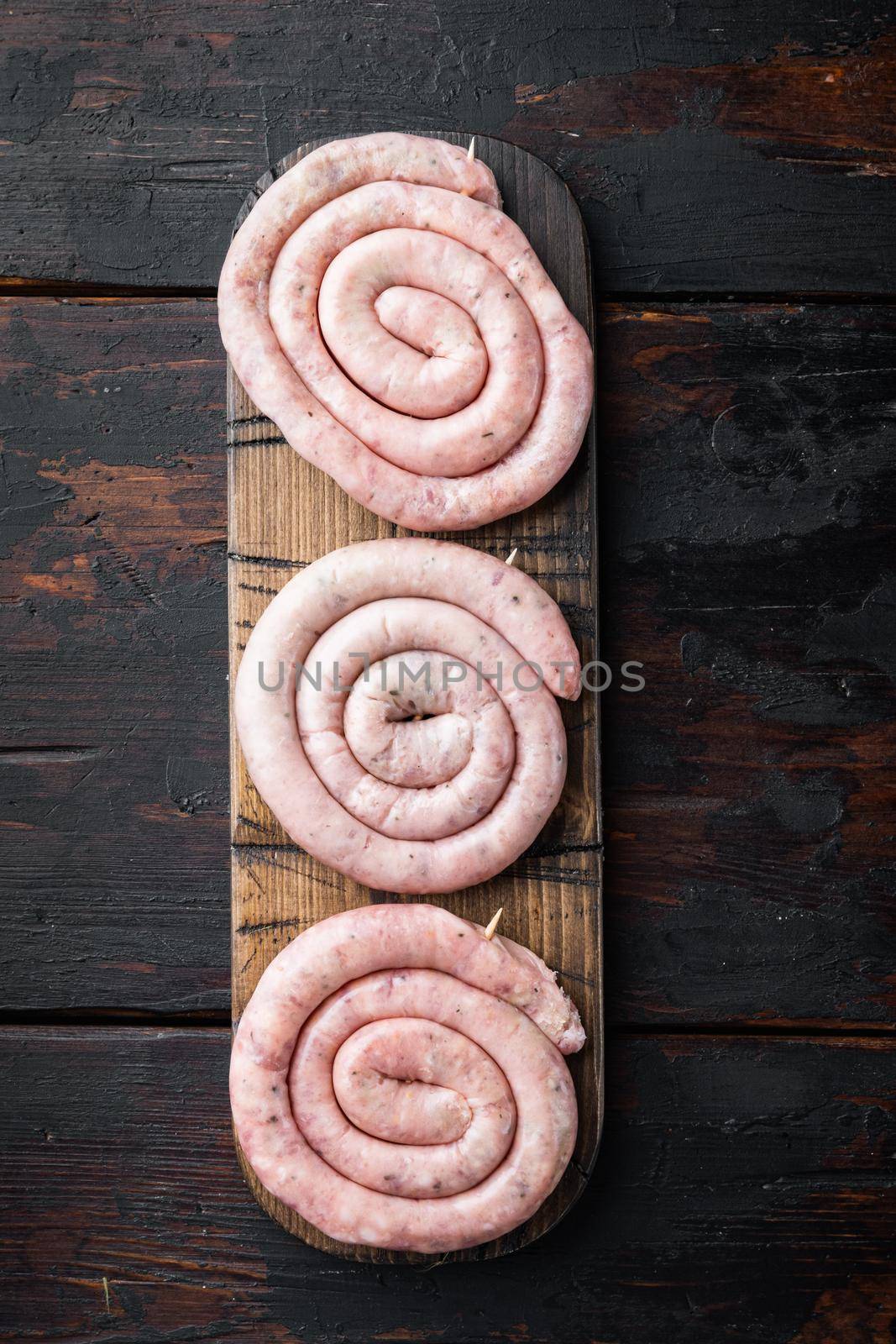 Traditional raw spiral pork sausages set, on old dark wooden table background, top view flat lay