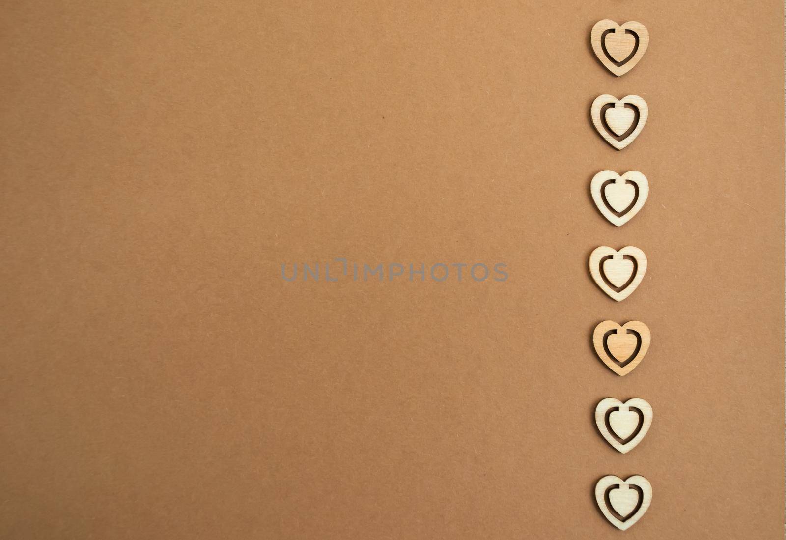 Wooden hearts on a pastel craft paper background. Abstract background with wood cut shapes. Sainte Valentine, mother's day, birthday greeting cards, invitations. Copy space.