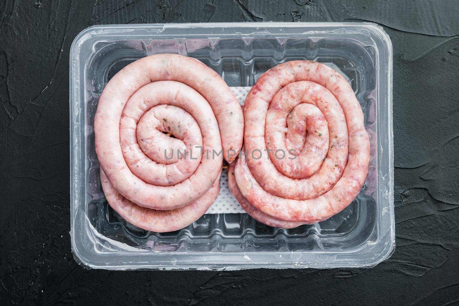 Raw meat sausage set, on black background, in plastic pack, top view flat lay