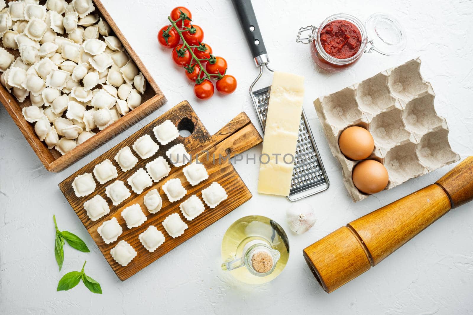 Raw Italian ravioli tortellini with fresh parmesan and basil , tomatoes set on wooden board, on white background, top view flat lay