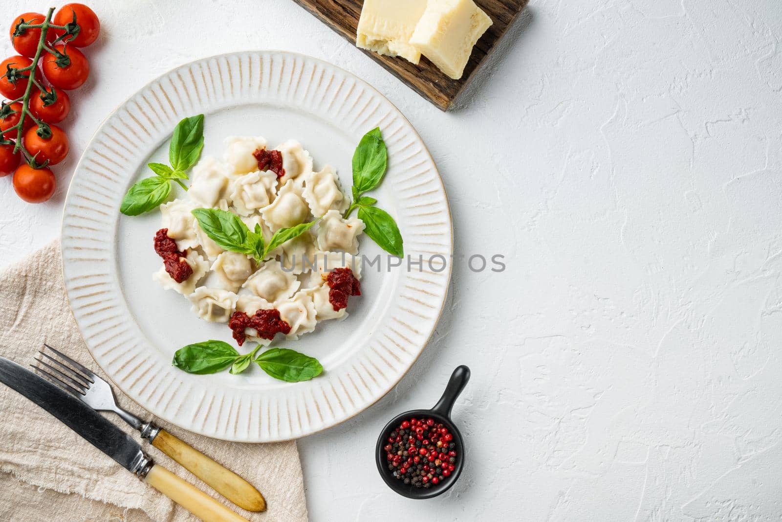 Appetizing ravioli with tomato sauce, cheese and basil set with basil parmesan and tomatoe on white plate, on white background, top view flat lay , with copyspace and space for text