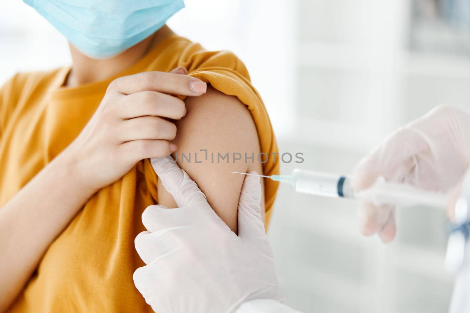 side view of doctor injecting vaccine into shoulder of patient wearing medical mask in hospital epidemic. High quality photo