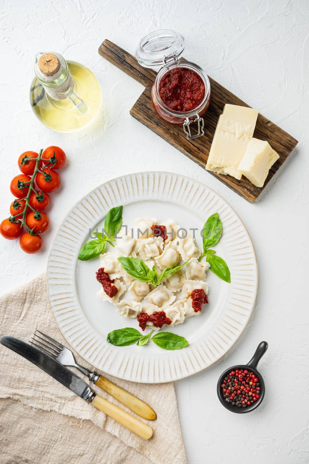 Ravioli pasta with mushroom cream sauce and cheese - Italian food style set with basil parmesan and tomatoe on white plate, on white background, top view flat lay