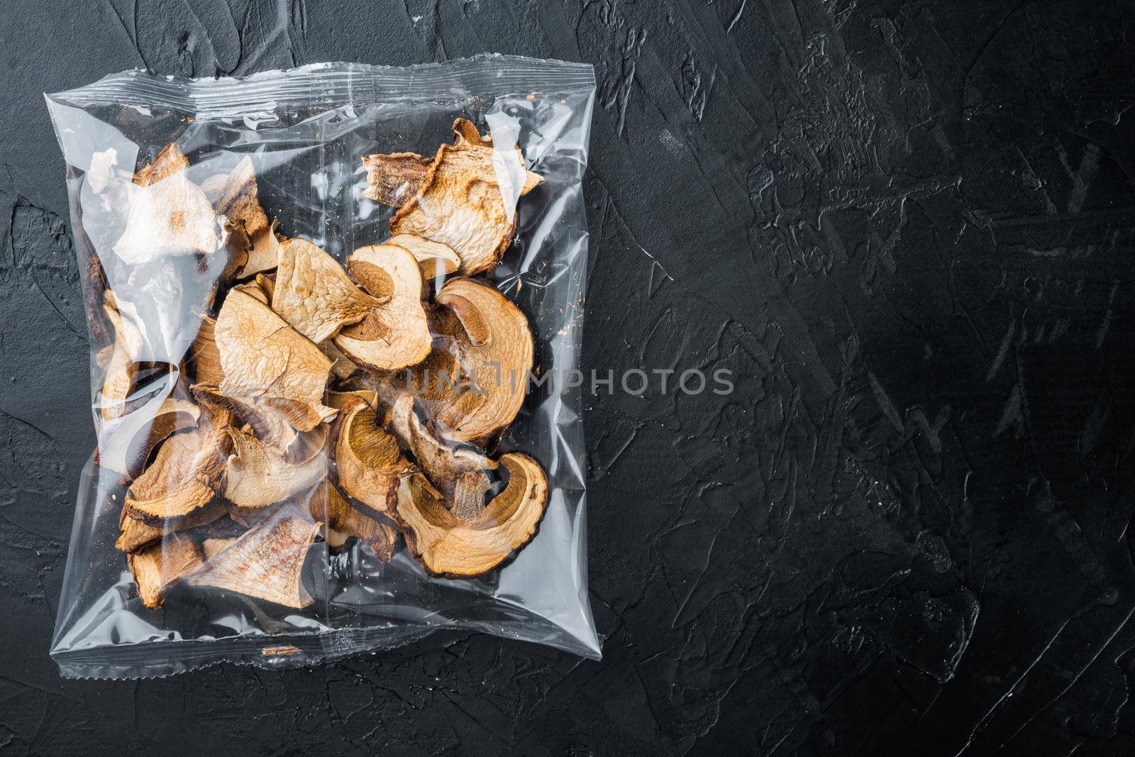 Dried mushrooms set, on black background, in plastic pack, top view flat lay , with space for text copyspace