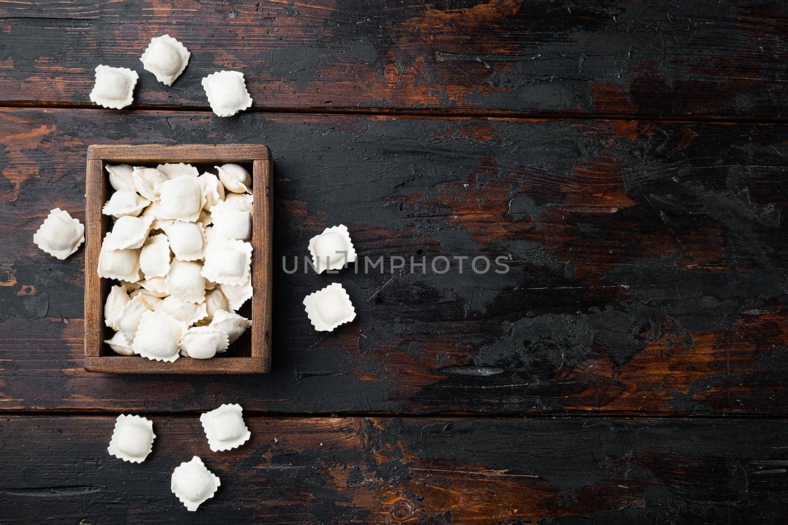 Frozen ravioli set in wooden box on old dark wooden table background, top view flat lay , with copyspace and space for text