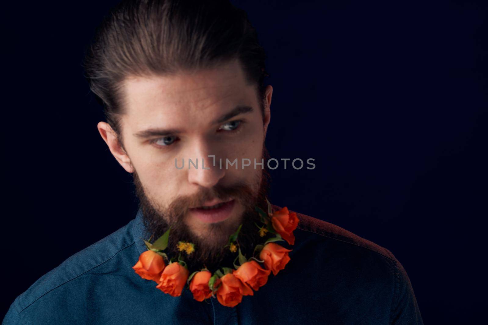 Bearded man flowers in a beard close-up romance dark background. High quality photo