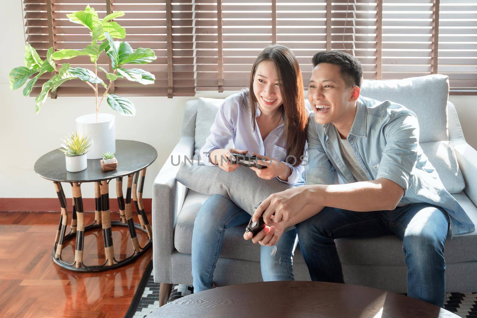 Asian couple lovers enjoy and play console game on vacation make more quality time of happiness together at home by Nuamfolio