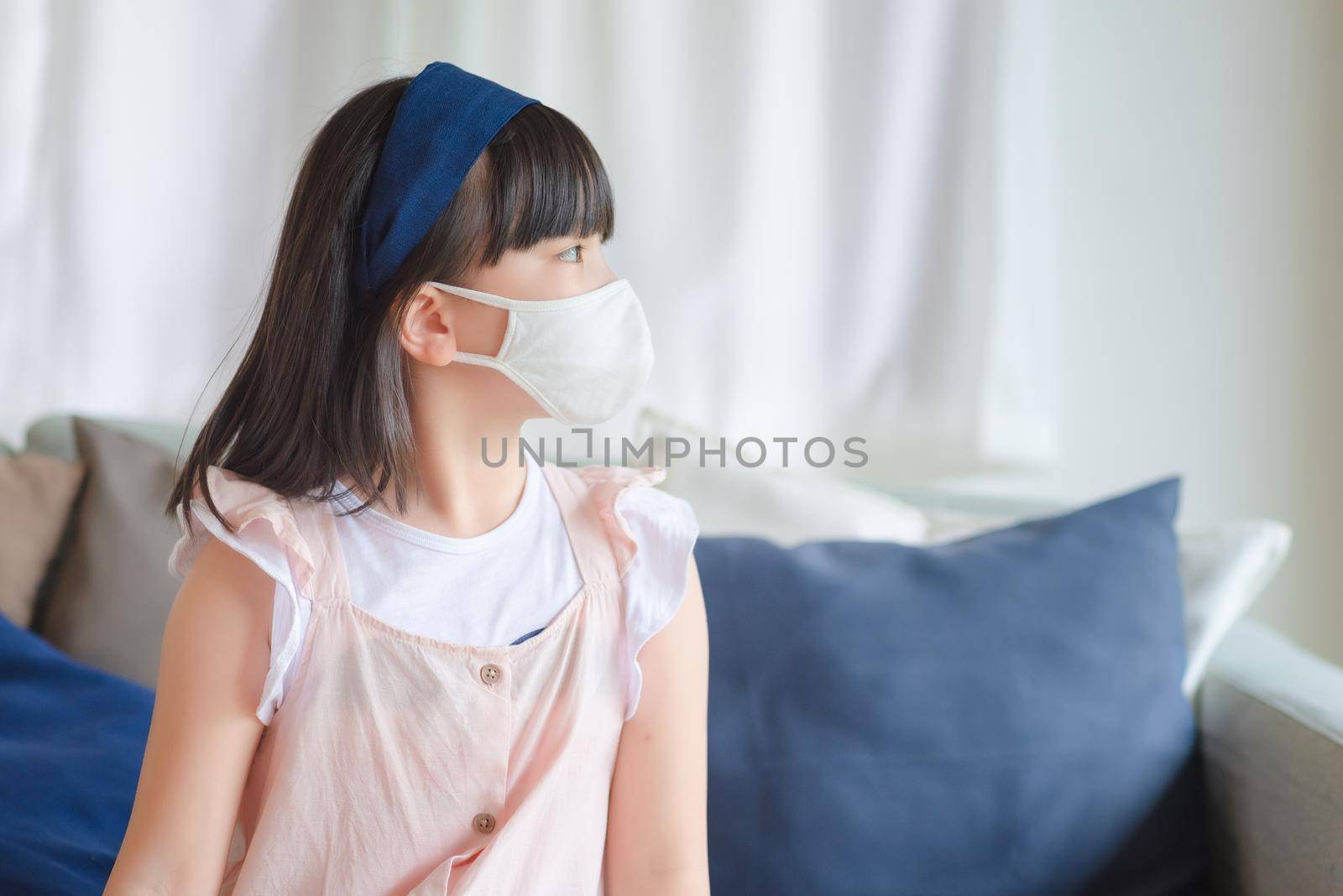 Asian little cute girl wearing hygienic face mask for prevent coronavirus or Covid-19 outbreak keep social distancing and stay at home. by Nuamfolio