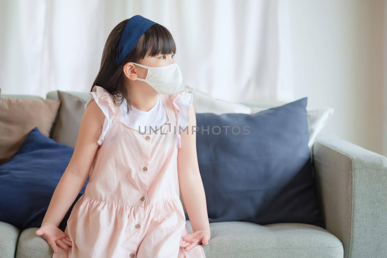 Asian little cute girl wearing hygienic face mask for prevent coronavirus or Covid-19 outbreak keep social distancing and stay at home.