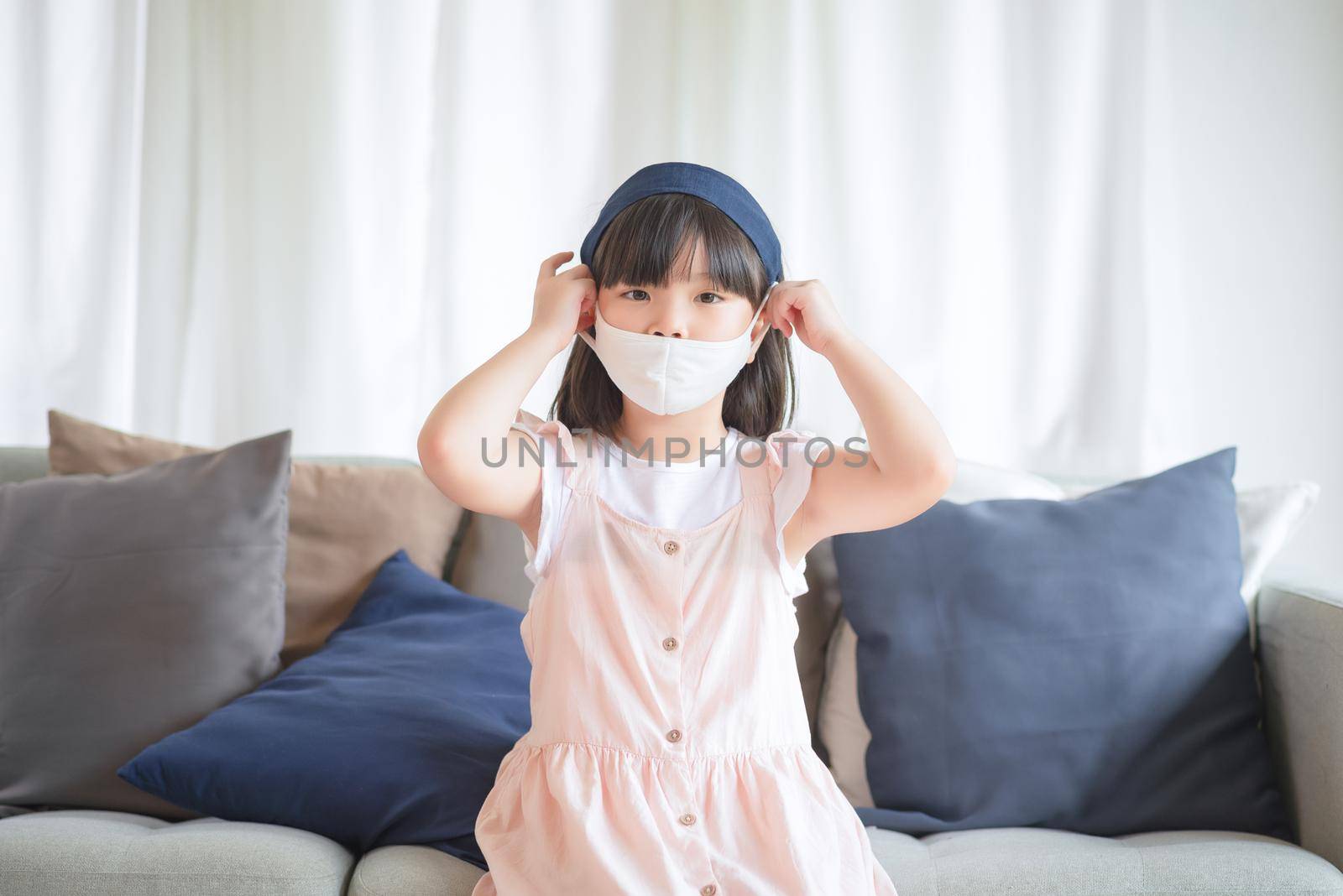 Asian little cute girl wearing hygienic face mask for prevent coronavirus or Covid-19 outbreak keep social distancing and stay at home.