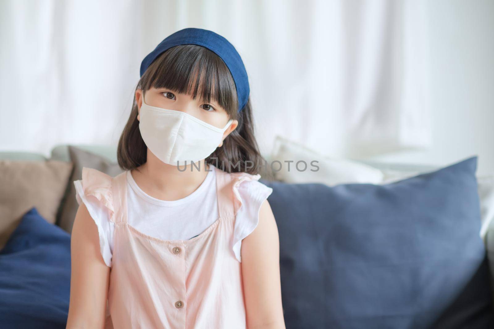 Asian little cute girl wearing hygienic face mask for prevent coronavirus or Covid-19 outbreak keep social distancing and stay at home.