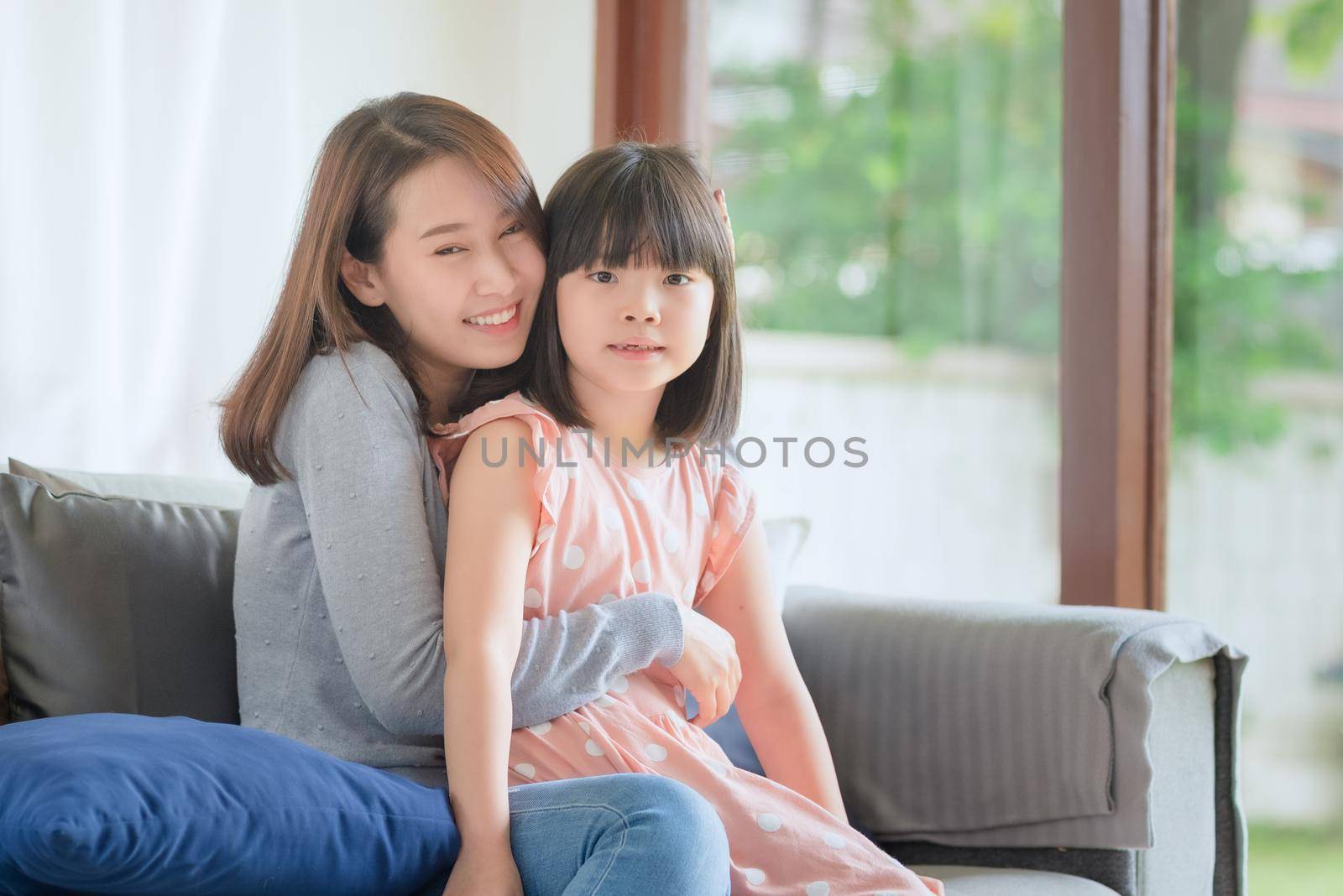 Asian mother feel hapiness during hug her cute daughter with love and care at home by Nuamfolio