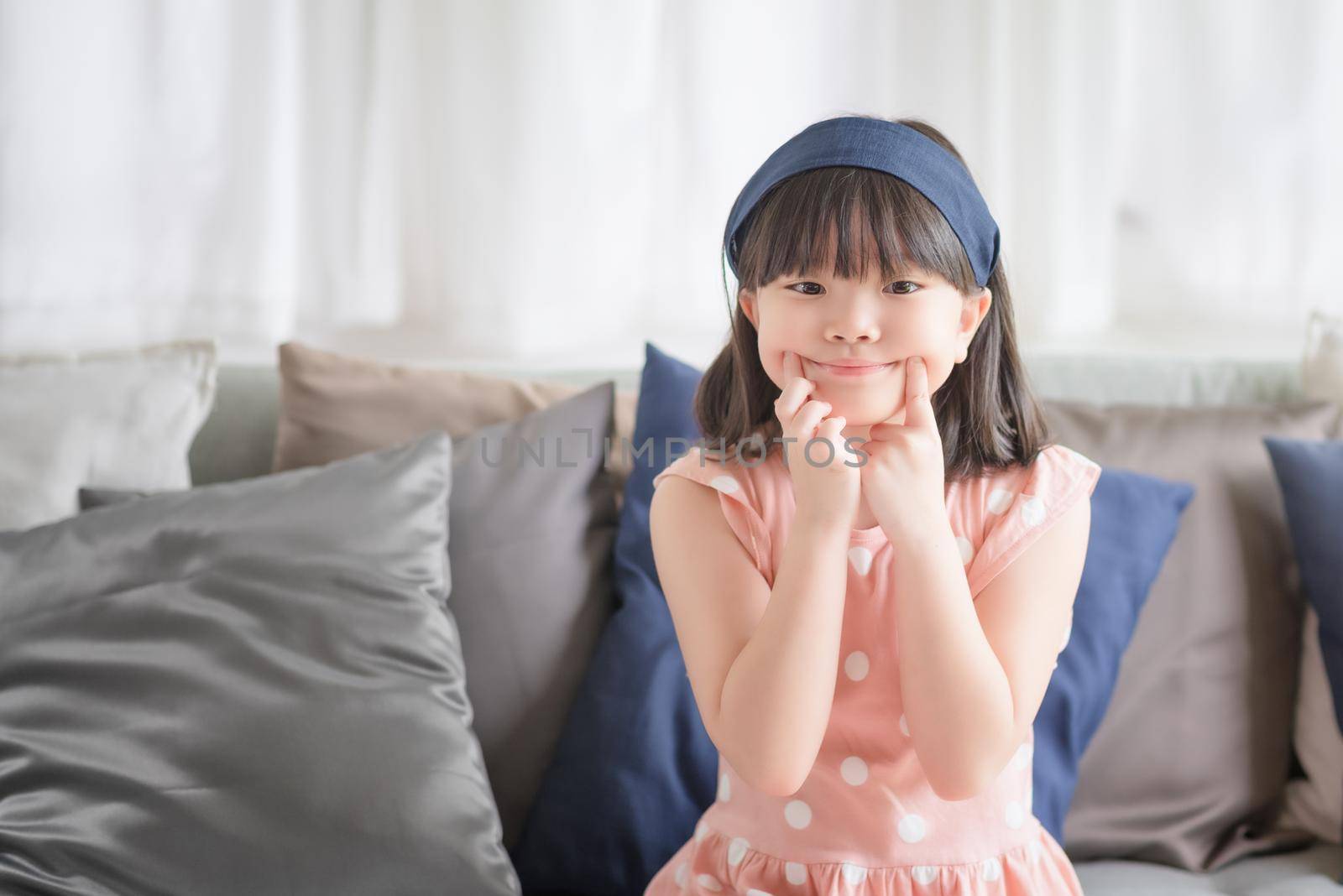 Portrait of asian little cute girl with happy charming smile in living room at home. by Nuamfolio