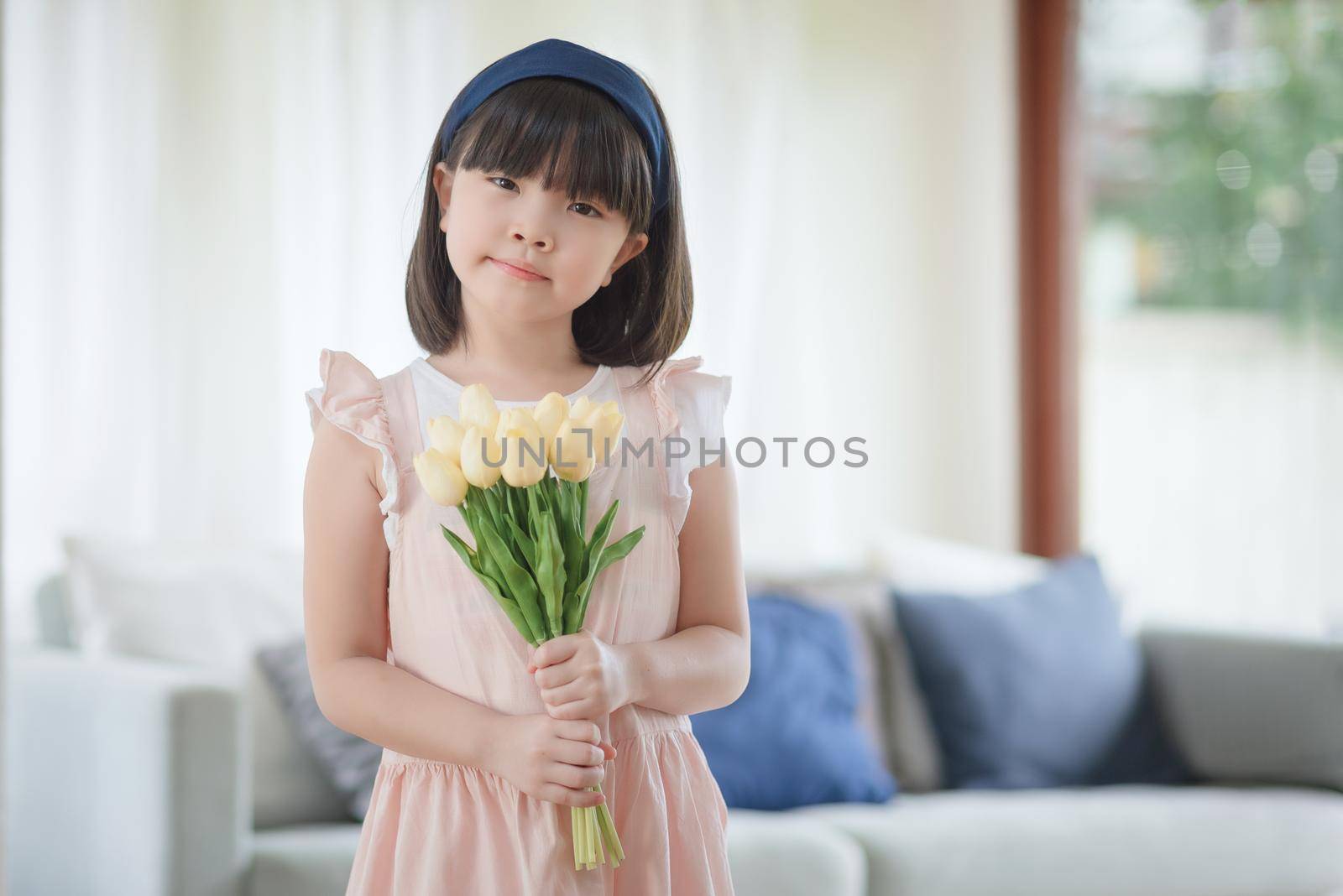 Portrait of asian little cute girl holdign flower with happy charming smile in living room at home. by Nuamfolio