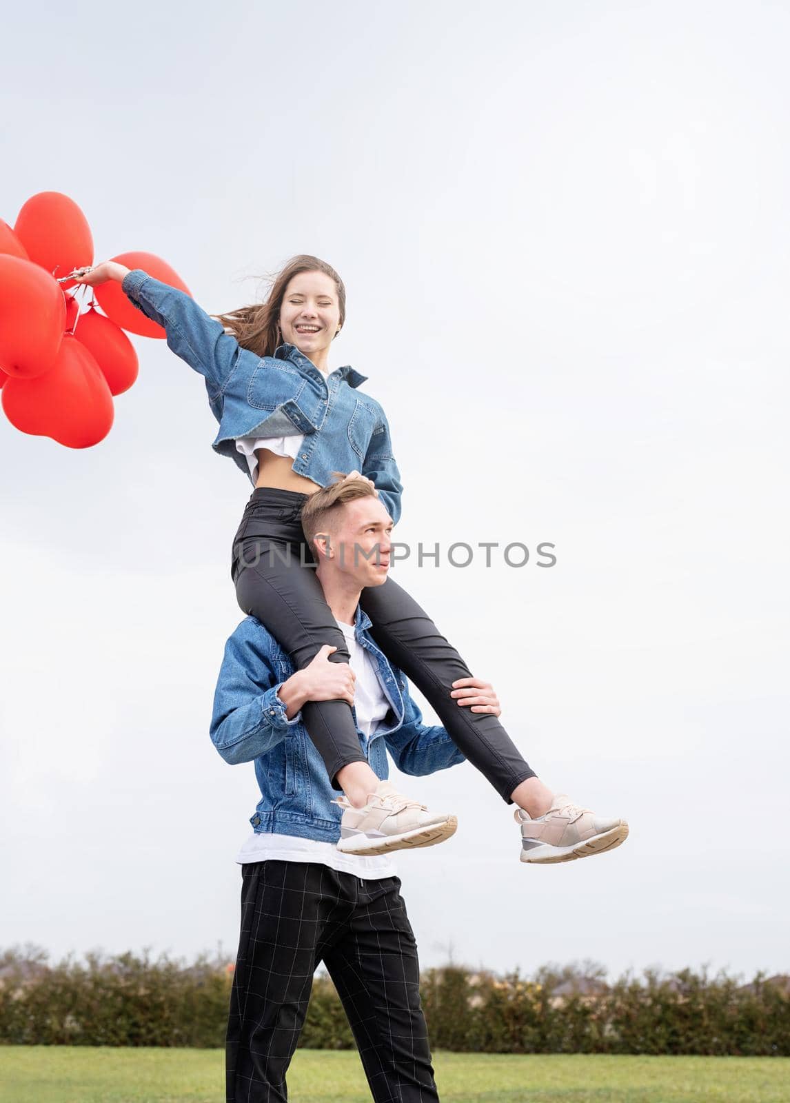 young loving couple with red balloons embracing outdoors having fun by Desperada