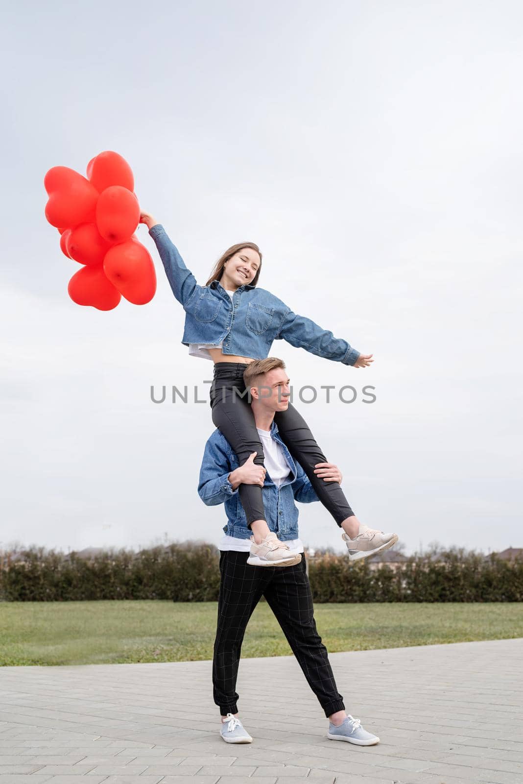 young loving couple with red balloons embracing outdoors having fun by Desperada