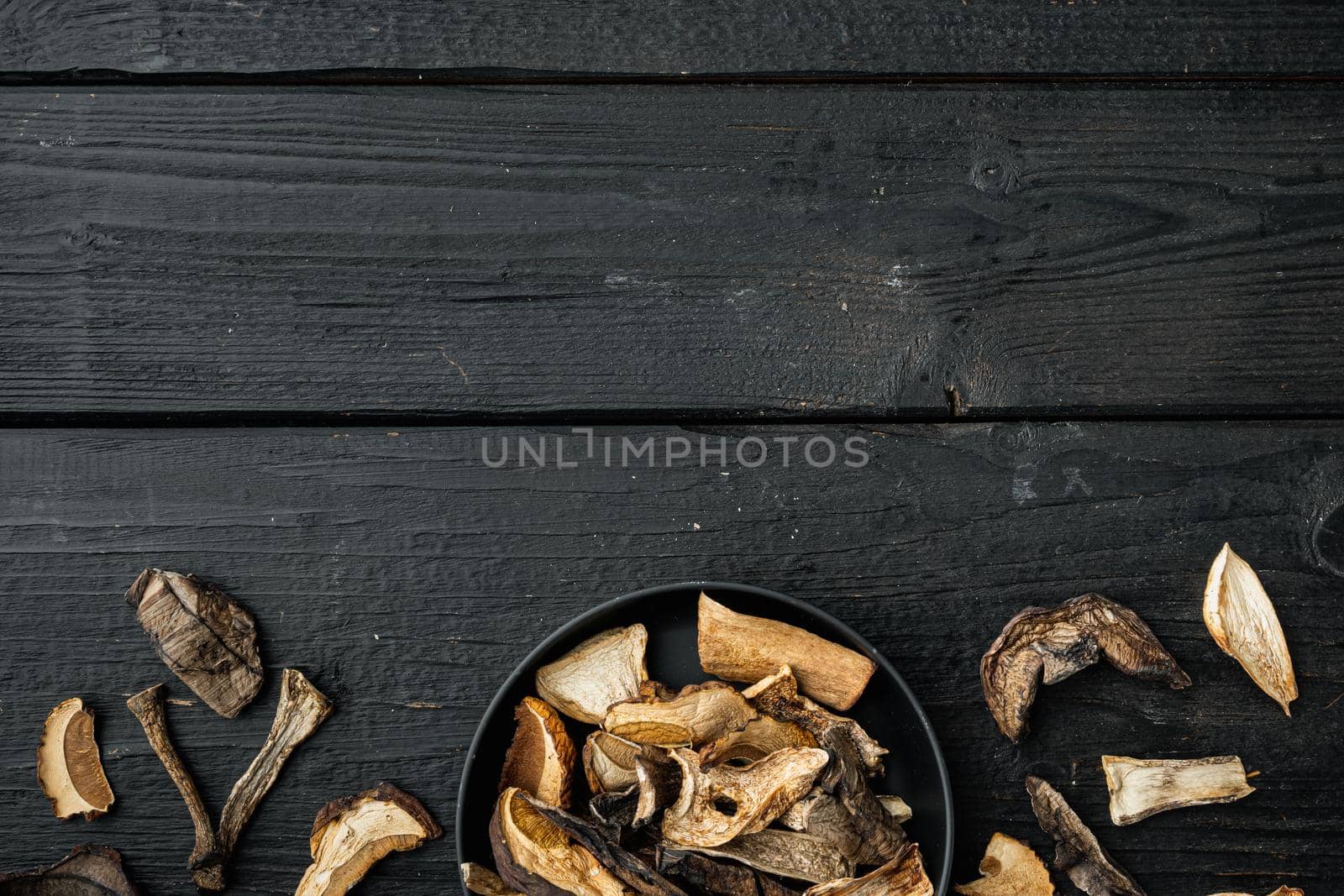 Mix of chopped wild dried mushrooms set, on black wooden table background, top view flat lay , with space for text copyspace