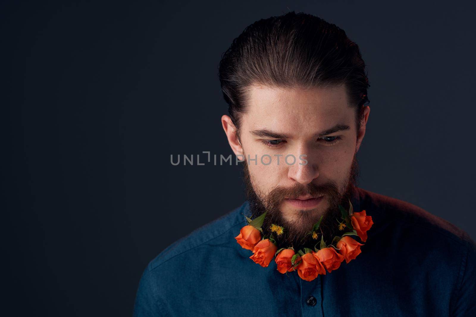 Bearded man flowers in a beard close-up romance dark background. High quality photo