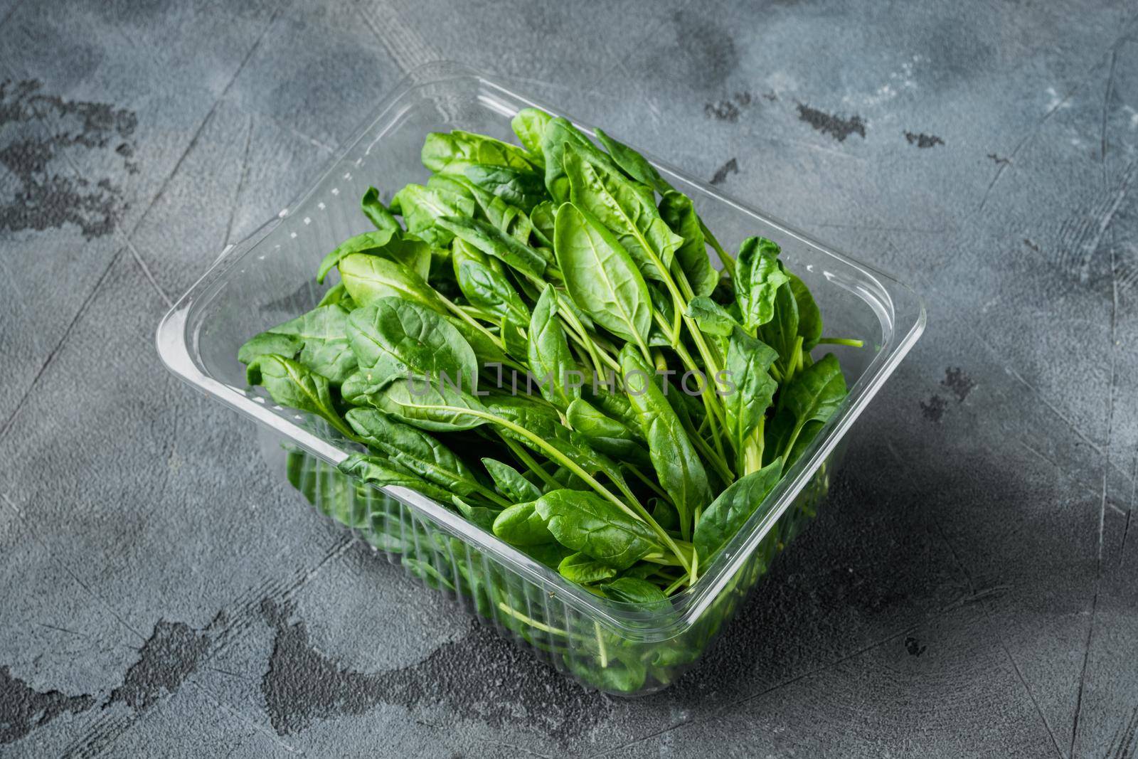 Washed fresh mini spinach set, on gray background, in plastic pack