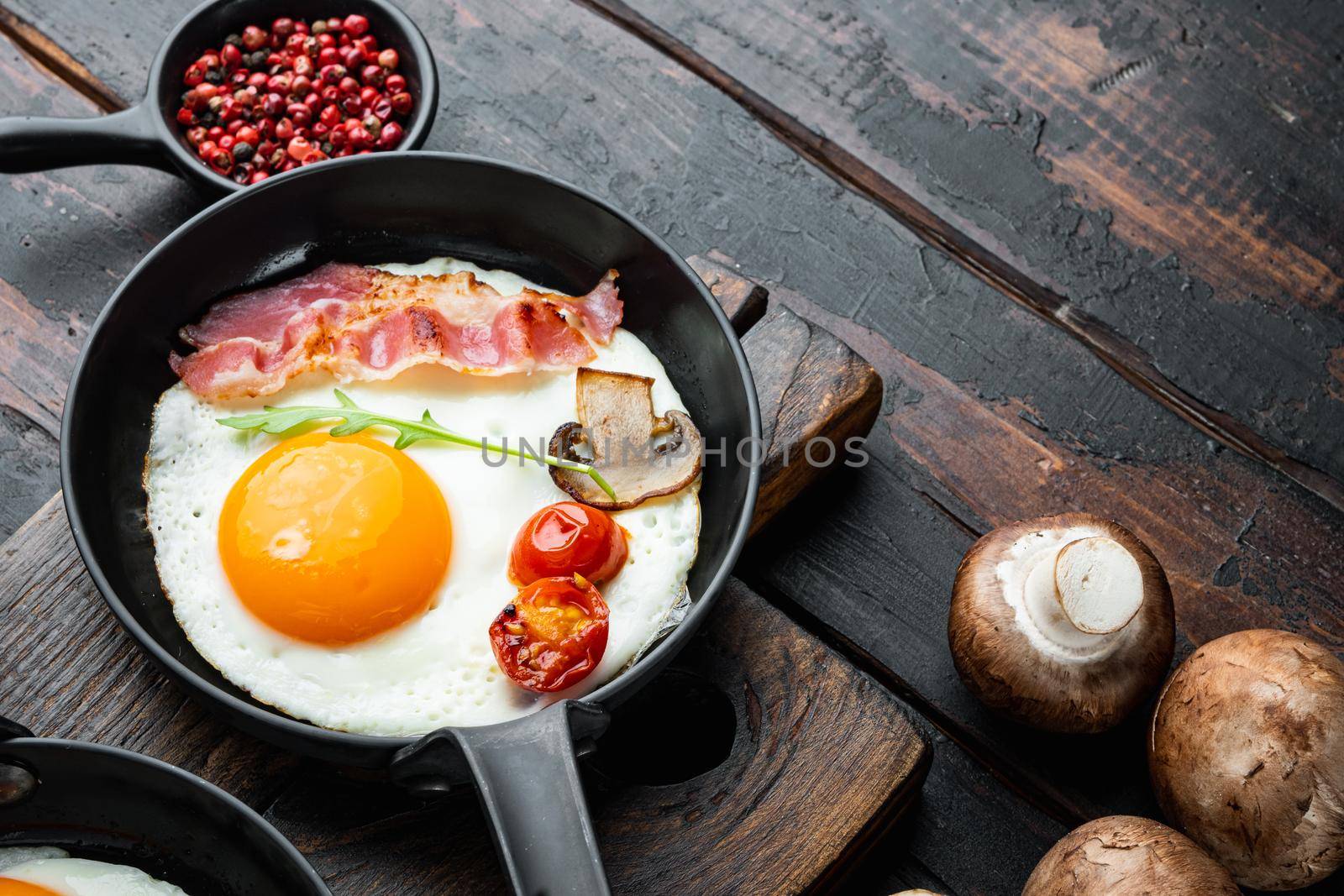 Scrambled eggs in frying pan with pork lard, bread and green feather in cast iron frying pan, on old dark wooden table background , with space for text copyspace