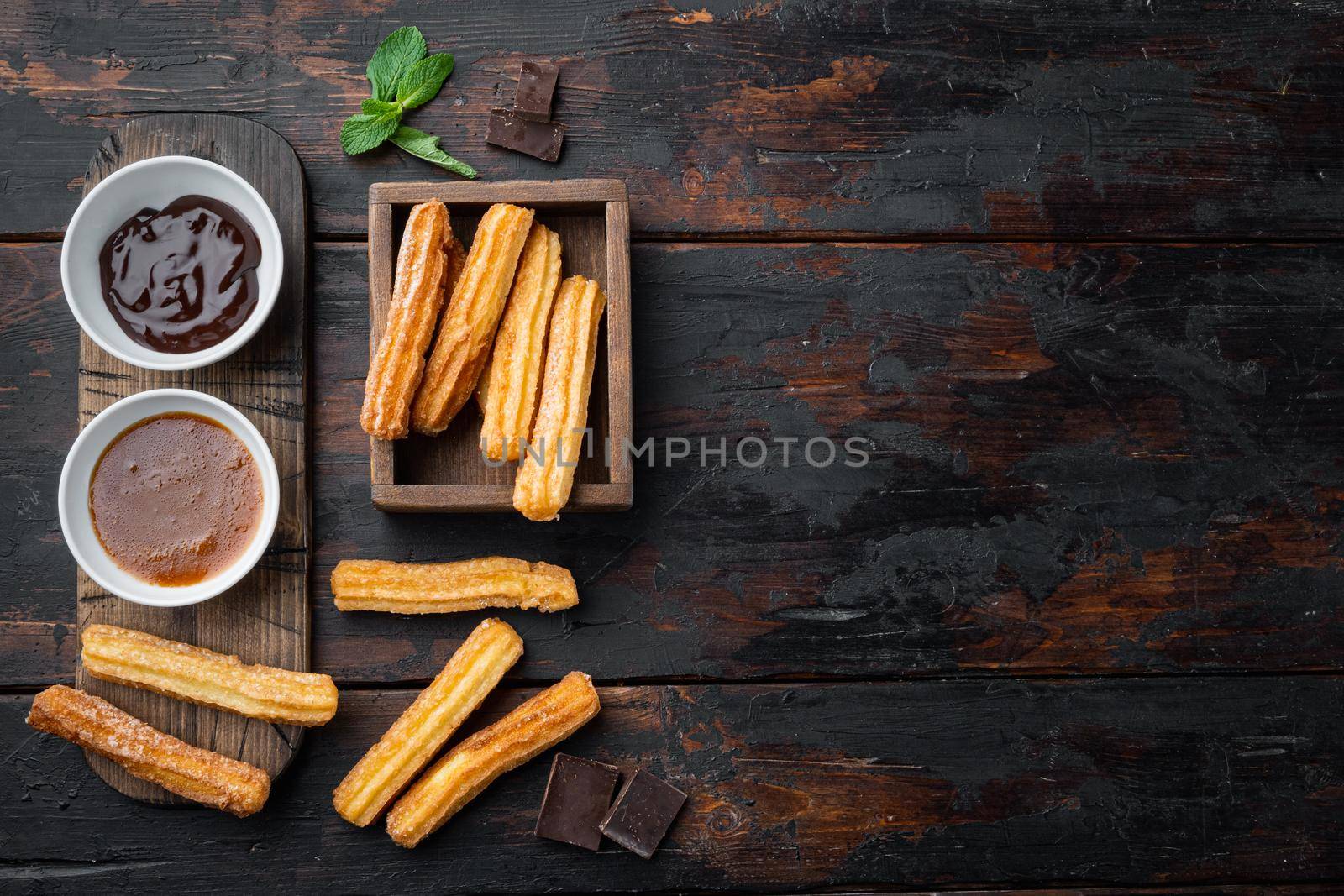 Traditional Spanish dessert churros with sugar and chocolate set, on old dark wooden table background, top view flat lay with space for text, copyspace