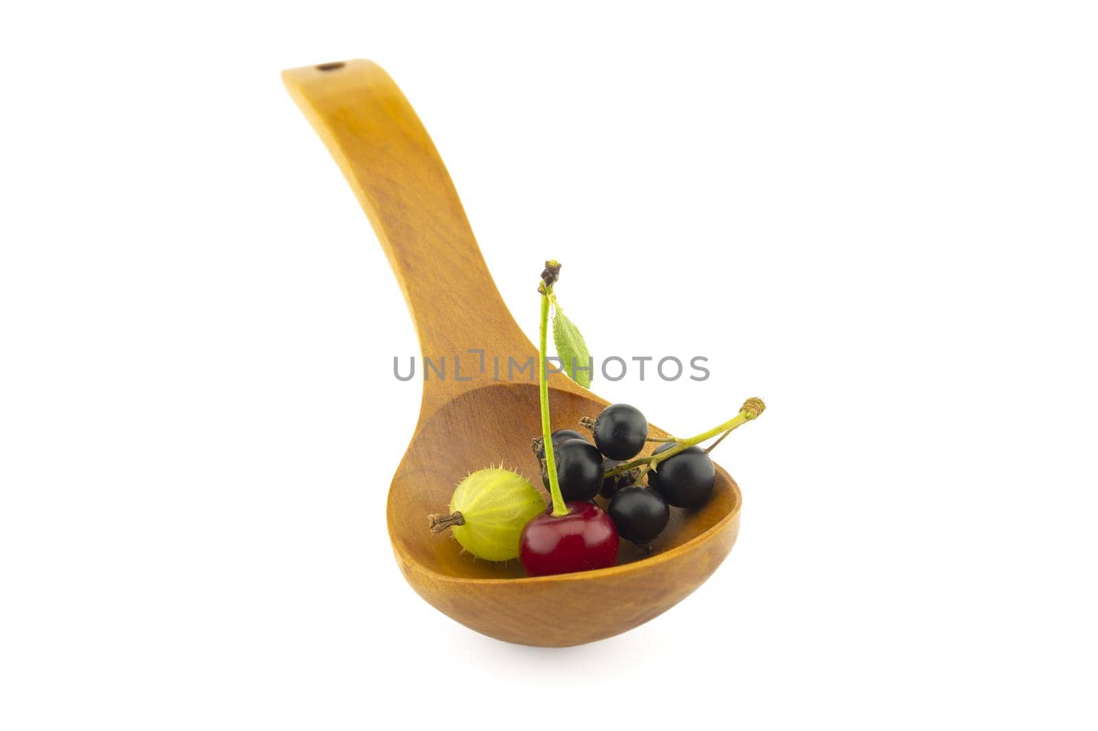 Gooseberries, cherries and black currants in a wooden spoon isolated on a white background