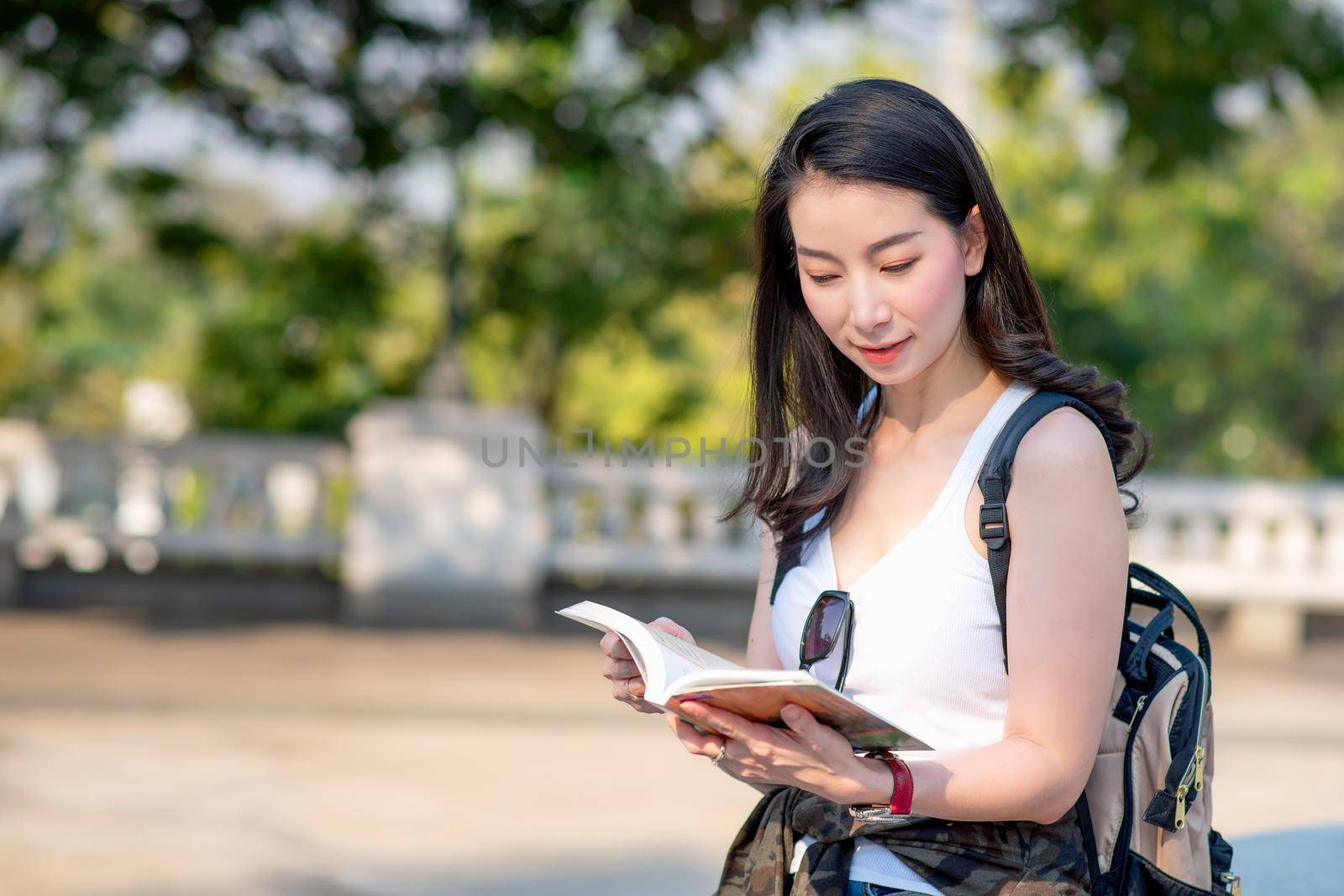 Beautiful asian tourist woman reading the travel guide book searching for for tourists sightseeing spot. Vacation travel in summer. by Nuamfolio