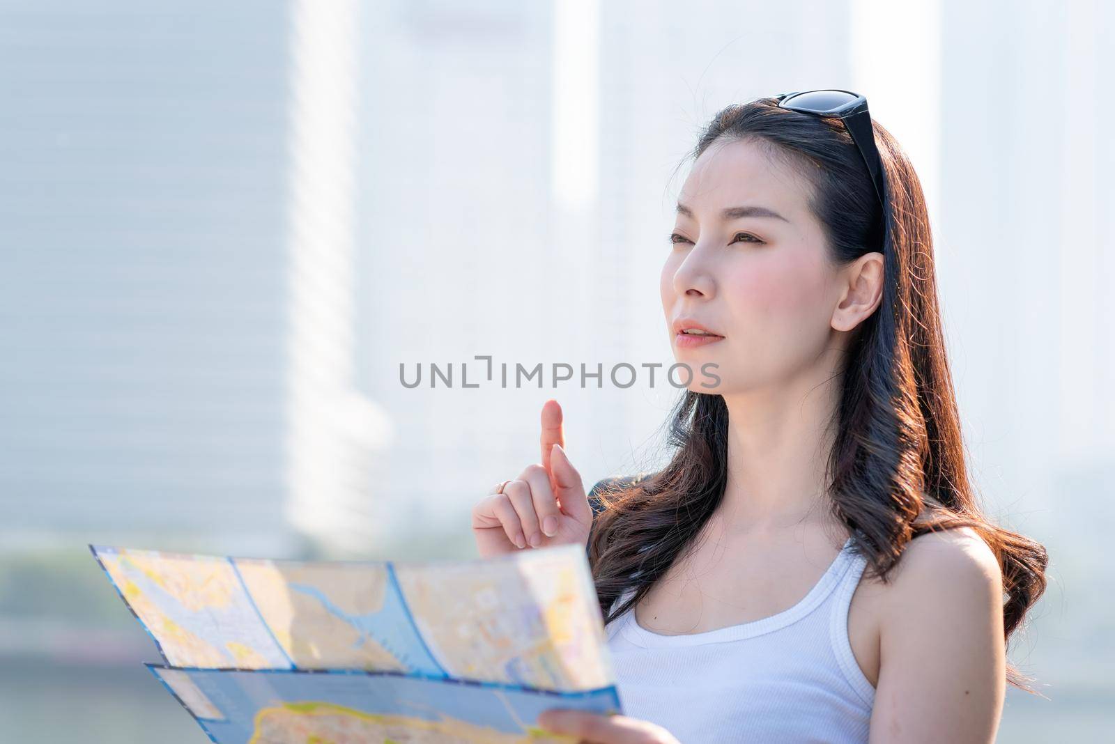 Beautiful asian tourist woman looking at map for searching location of landmark. Vacation travel in summer