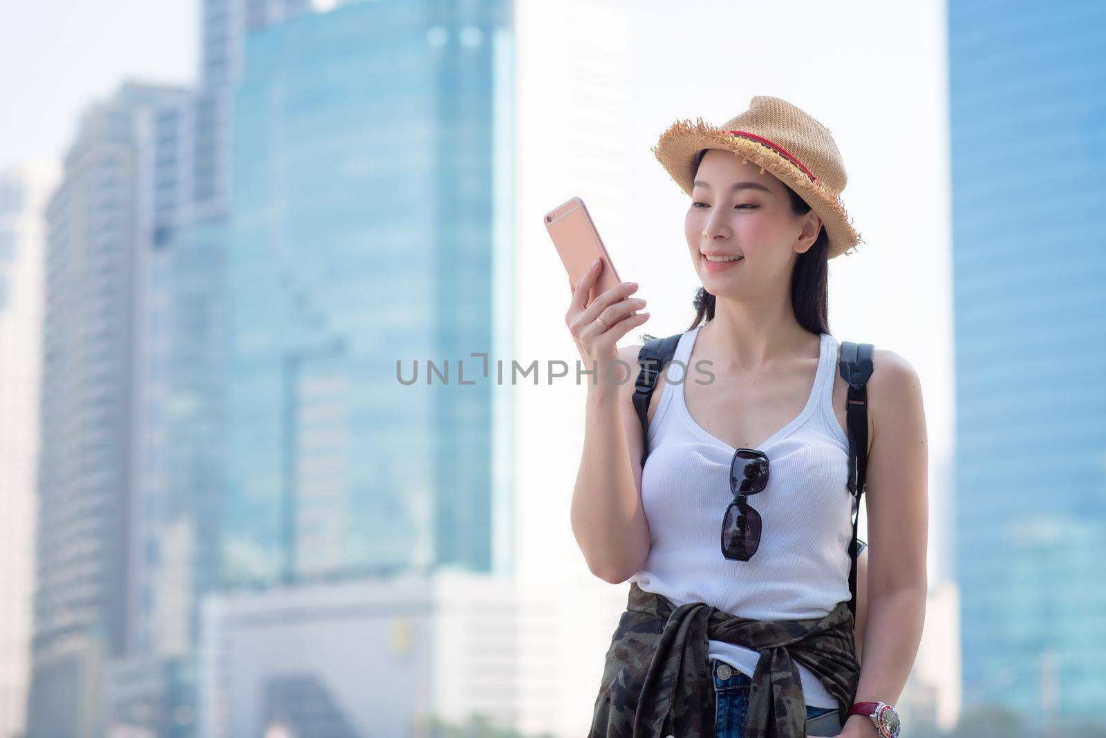 Beautiful asian tourist woman looking at mobile phone for searching location of landmark. Vacation travel in summer