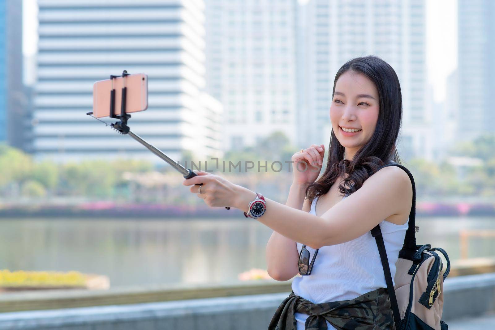 Beautiful asian tourist woman use video call via a smartphone in urban city downtown. Vacation travel in summer. by Nuamfolio