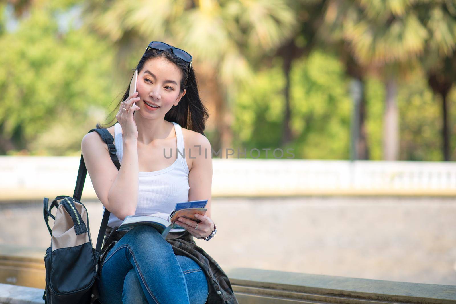 Beautiful asian tourist woman reading the travel guide book searching for for tourists sightseeing spot. Vacation travel in summer. by Nuamfolio