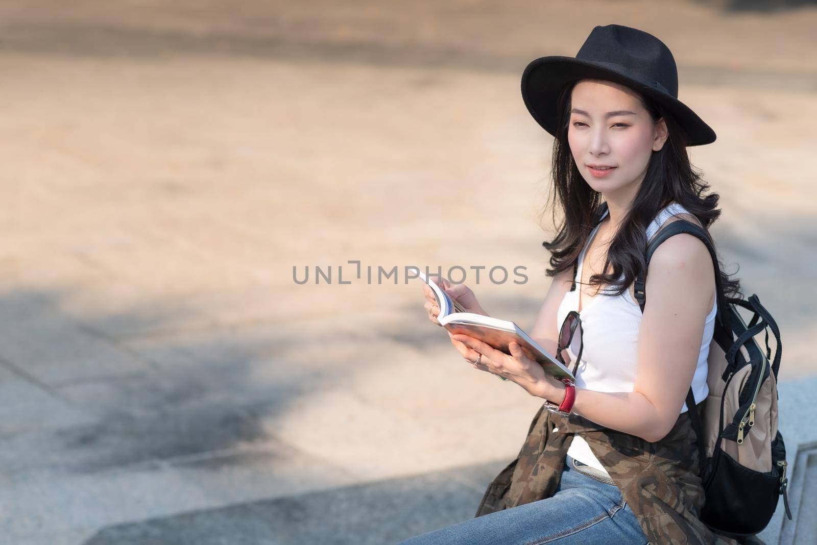 Beautiful asian tourist woman looking at travel guide book for searching location of landmark. Vacation travel in summer by Nuamfolio