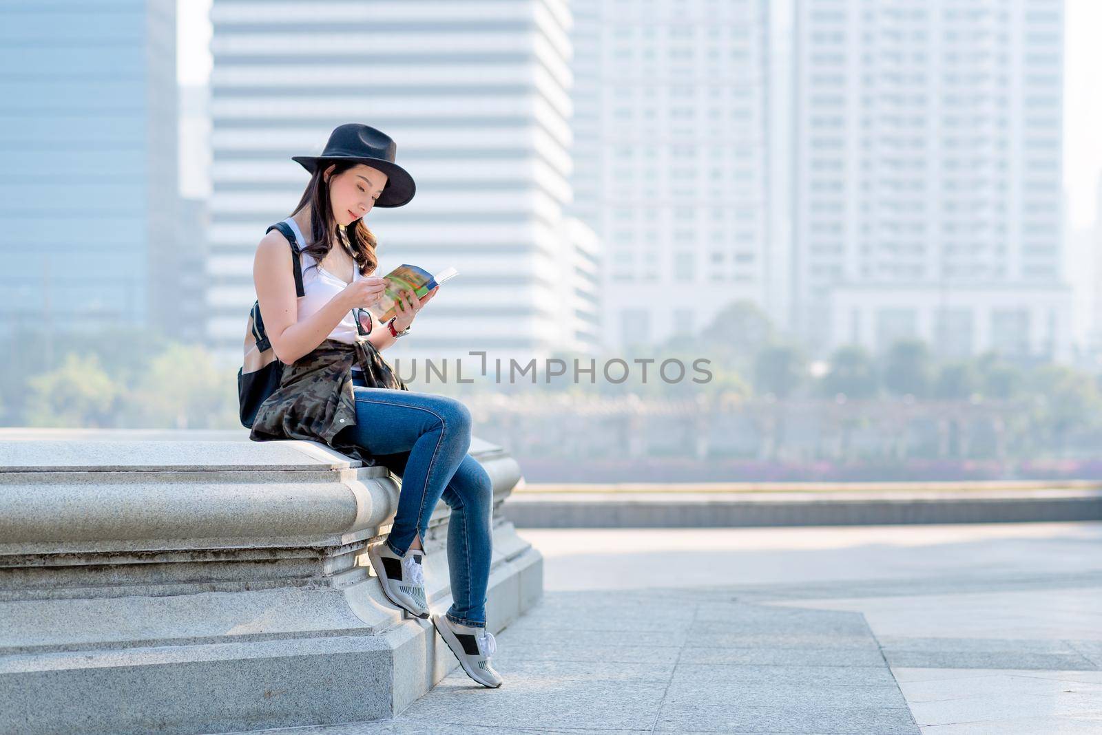 Beautiful asian tourist woman reading travel guide book for searching location of tourist sightseeing. Vacation travel in summer by Nuamfolio