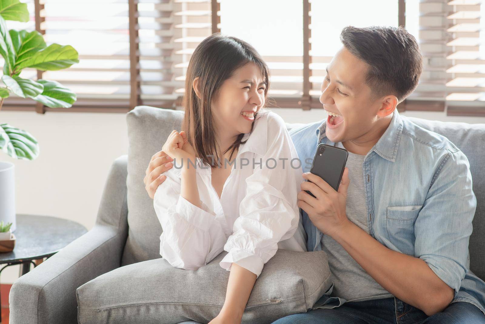 Asian couple lovers enjoy listening streaming online music via smartphone at home by Nuamfolio