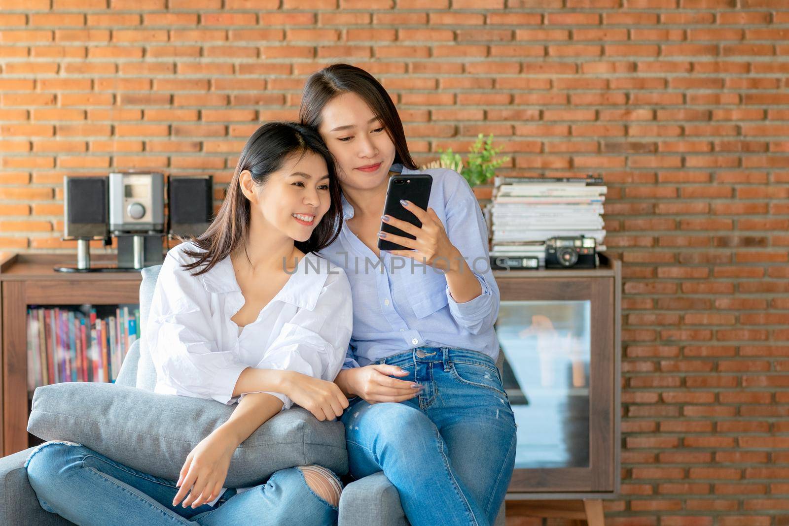 Two young female using mobile phone and internet technology to use video call to other friends during stay safe at home by Nuamfolio