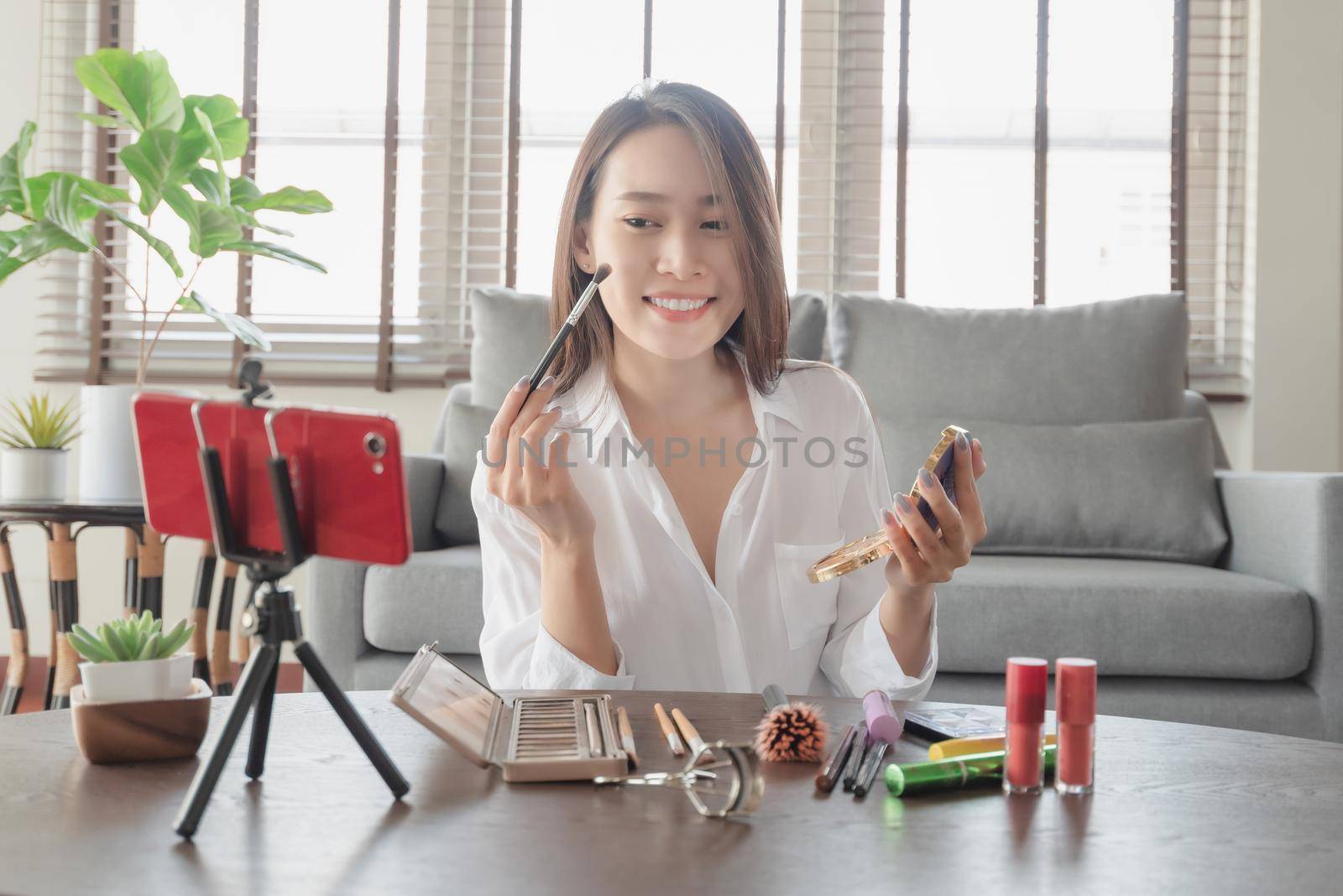 Young female beauty influencer making a video tutorial for her beauty channel on cosmetics during stay safe at home