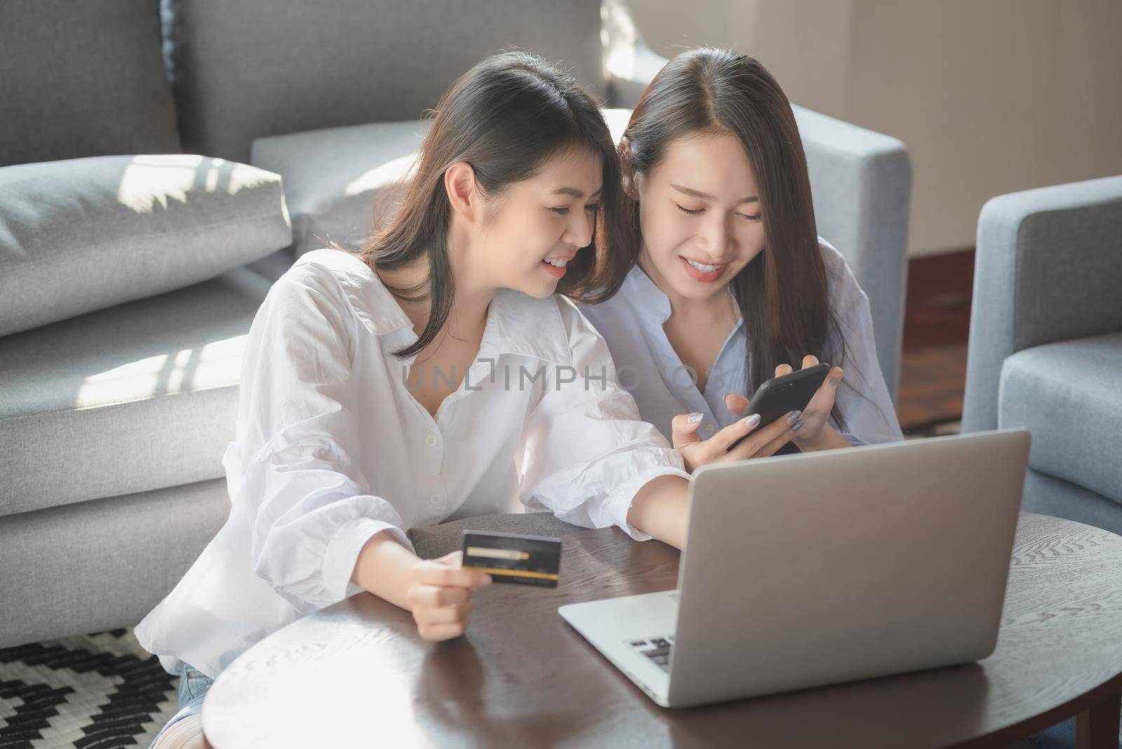 Two young woman use laptop computer to shopping online via internet during stay safe at home by Nuamfolio