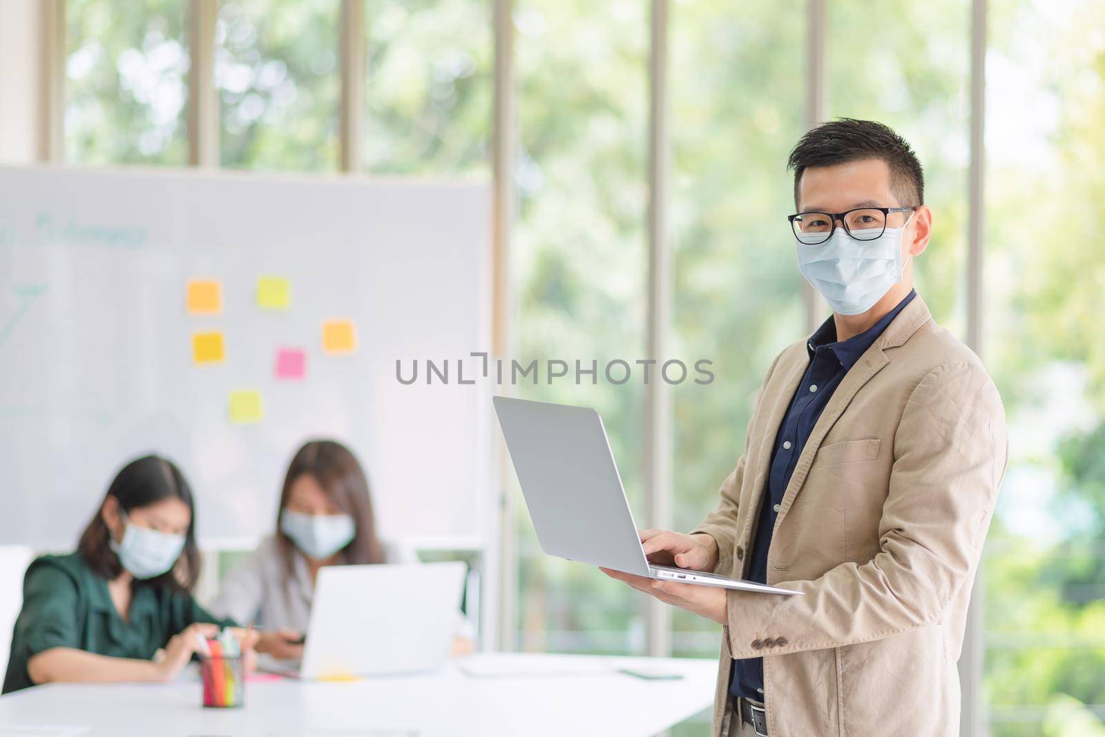 Business employees wearing mask during work in office to keep hygiene follow company policy. by Nuamfolio